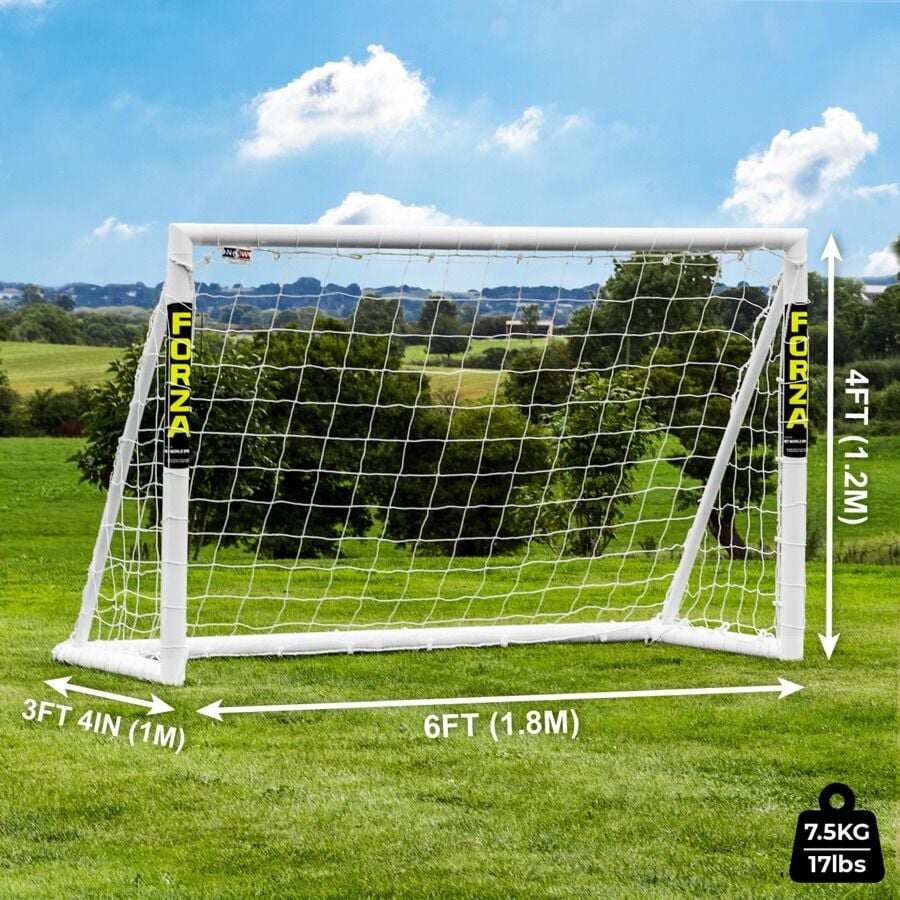 Footfall Pallone da calcio e delle porte sul campo di gioco attraverso la porta net Foto stock
